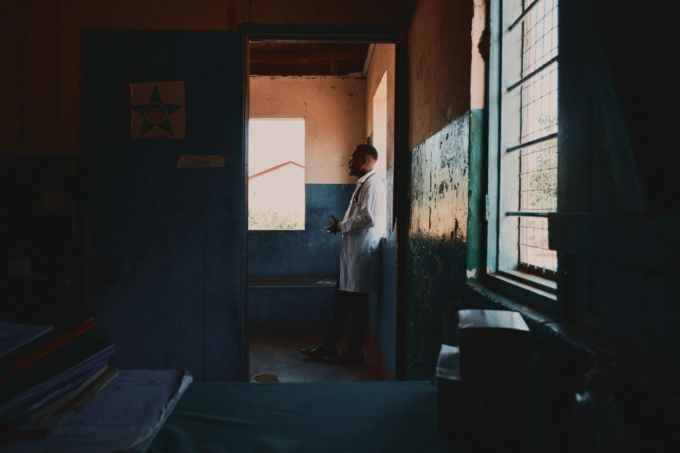 Light falls through a doorway into a dim clinic room