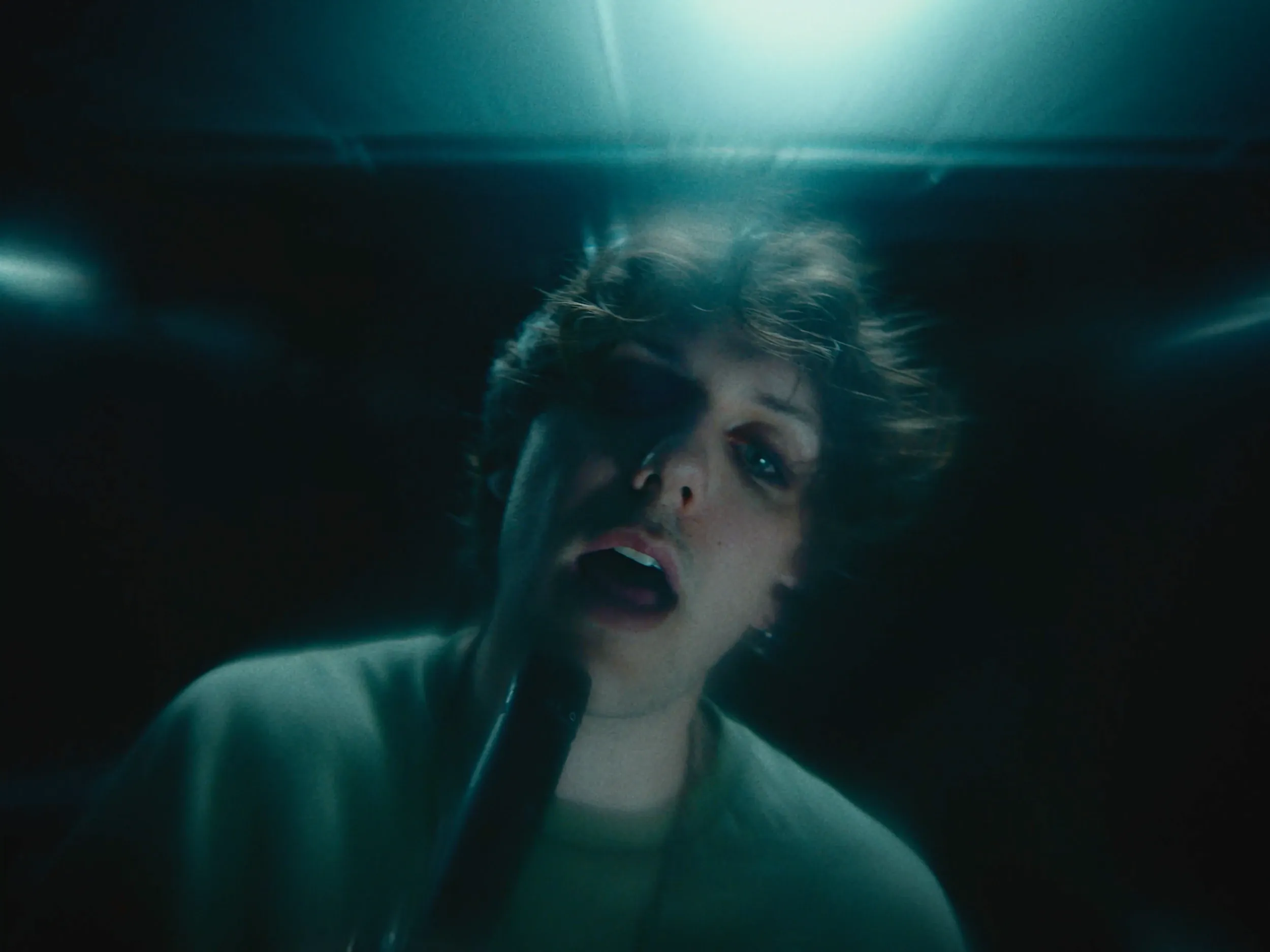 The singer, eyes half closed, in teal light