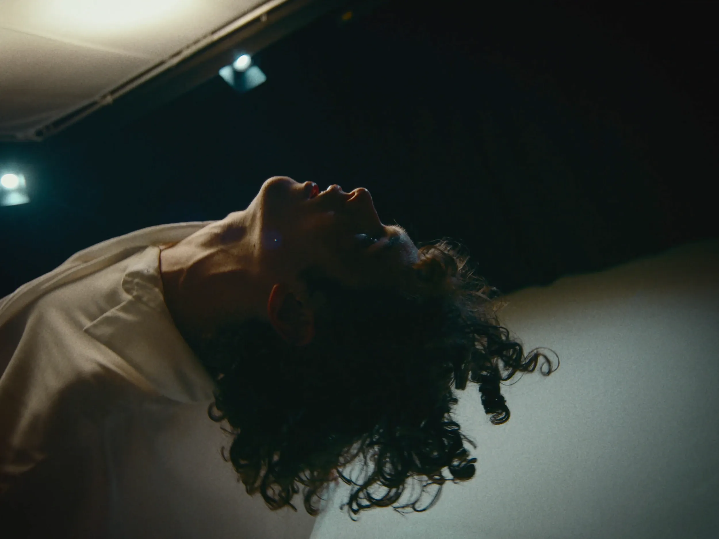 A dancer arches back, curly hair falling toward the floor
