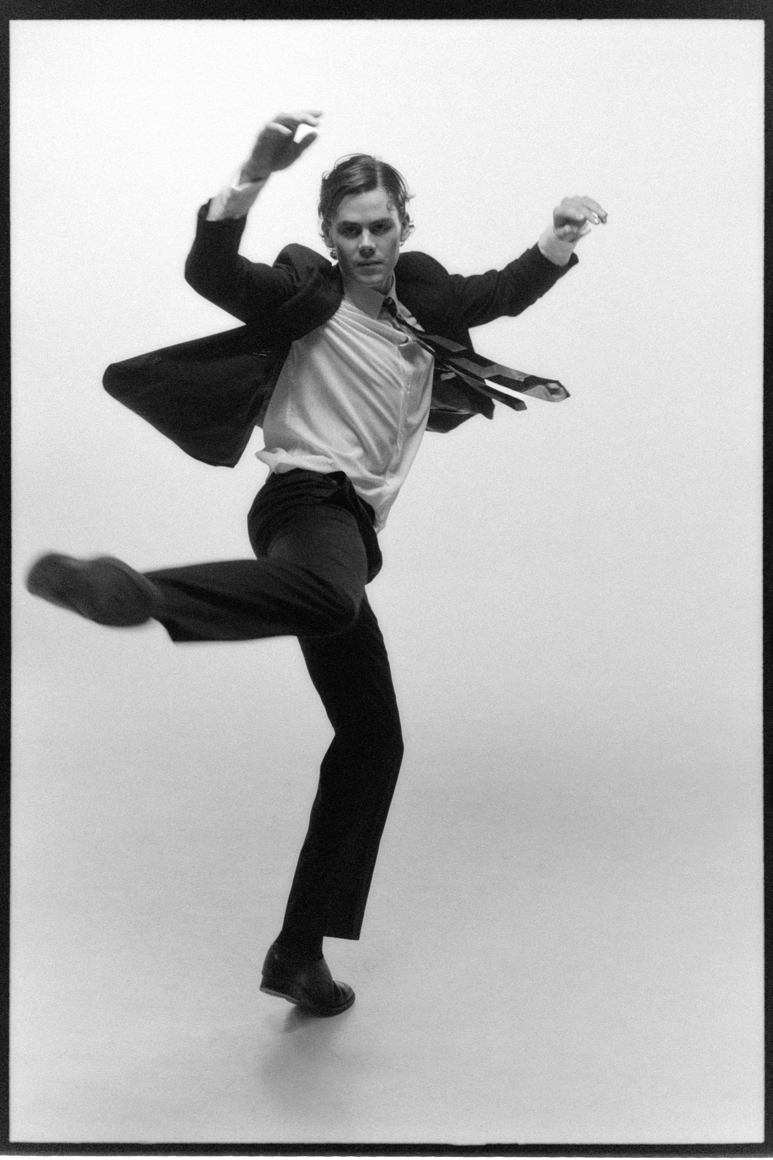 Dancer mid-leap, jacket flying open, one leg kicked forward