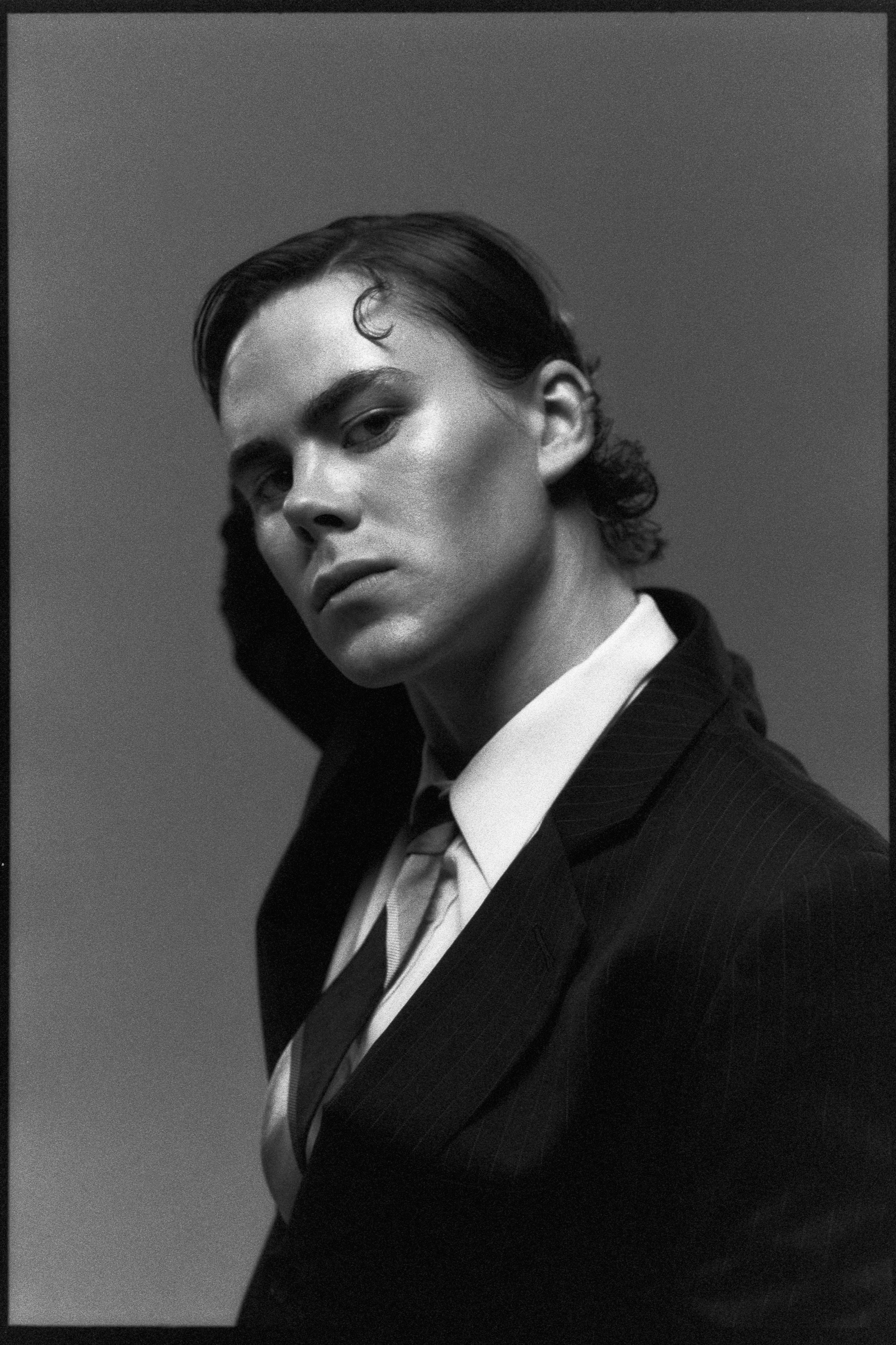 Portrait of the dancer, head tilted, slicked hair, suit and tie