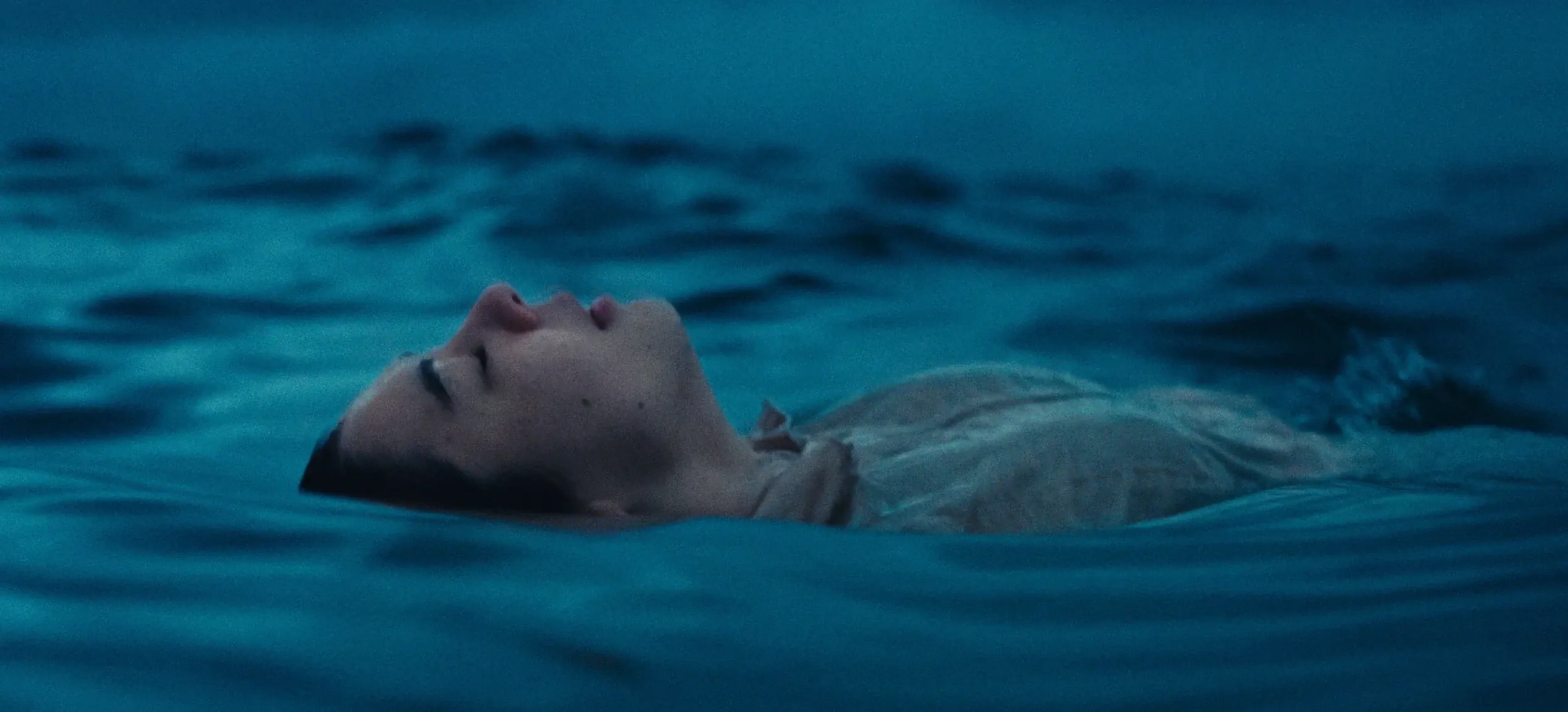 A woman floats on her back in dark blue water