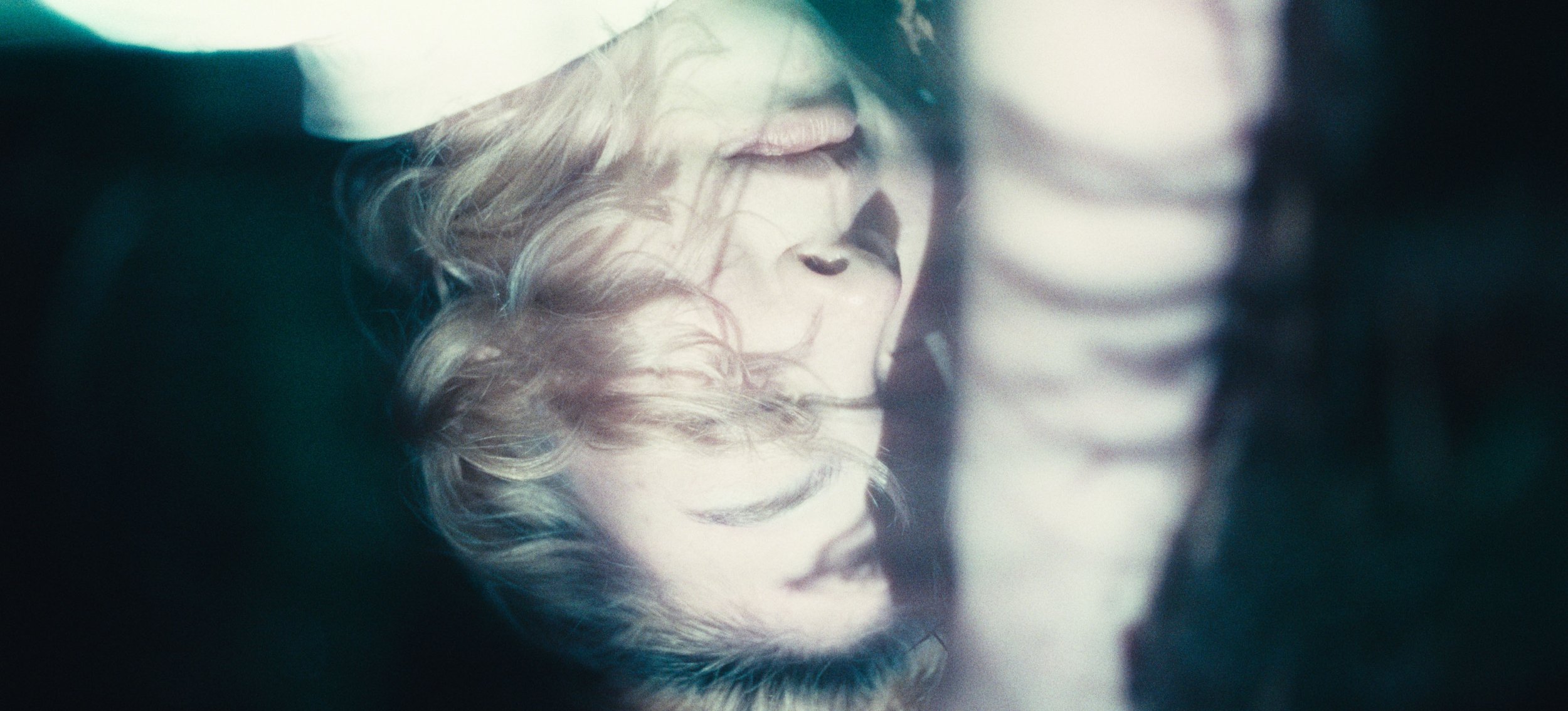 A woman's face and fair hair, upside down in soft light
