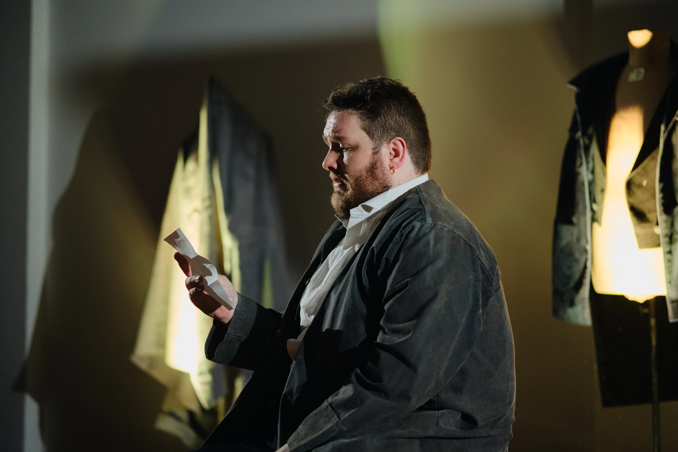 A singer sits reading a letter in warm window light