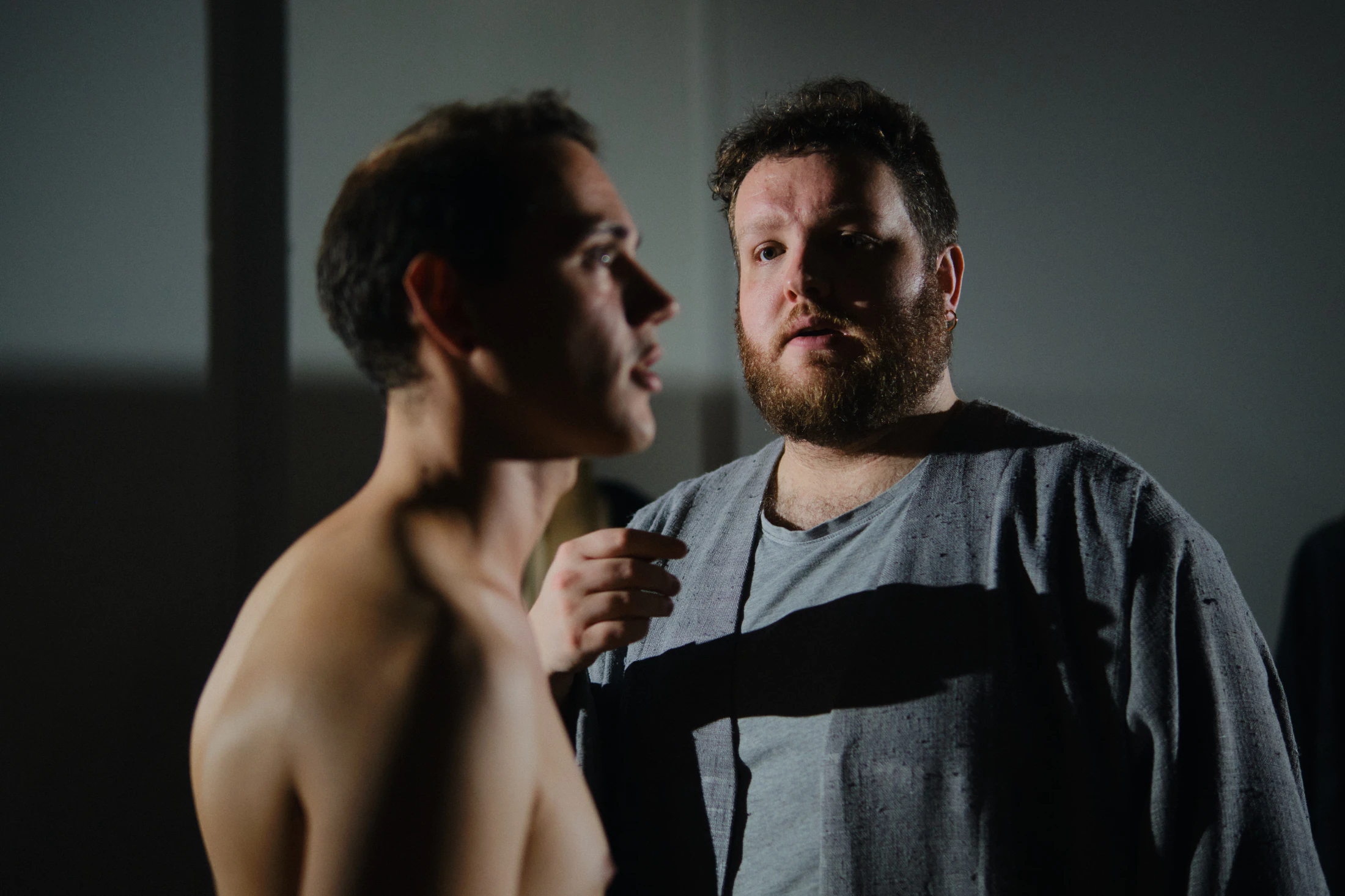 Two singers face each other, one shirtless, in a scene at The Church