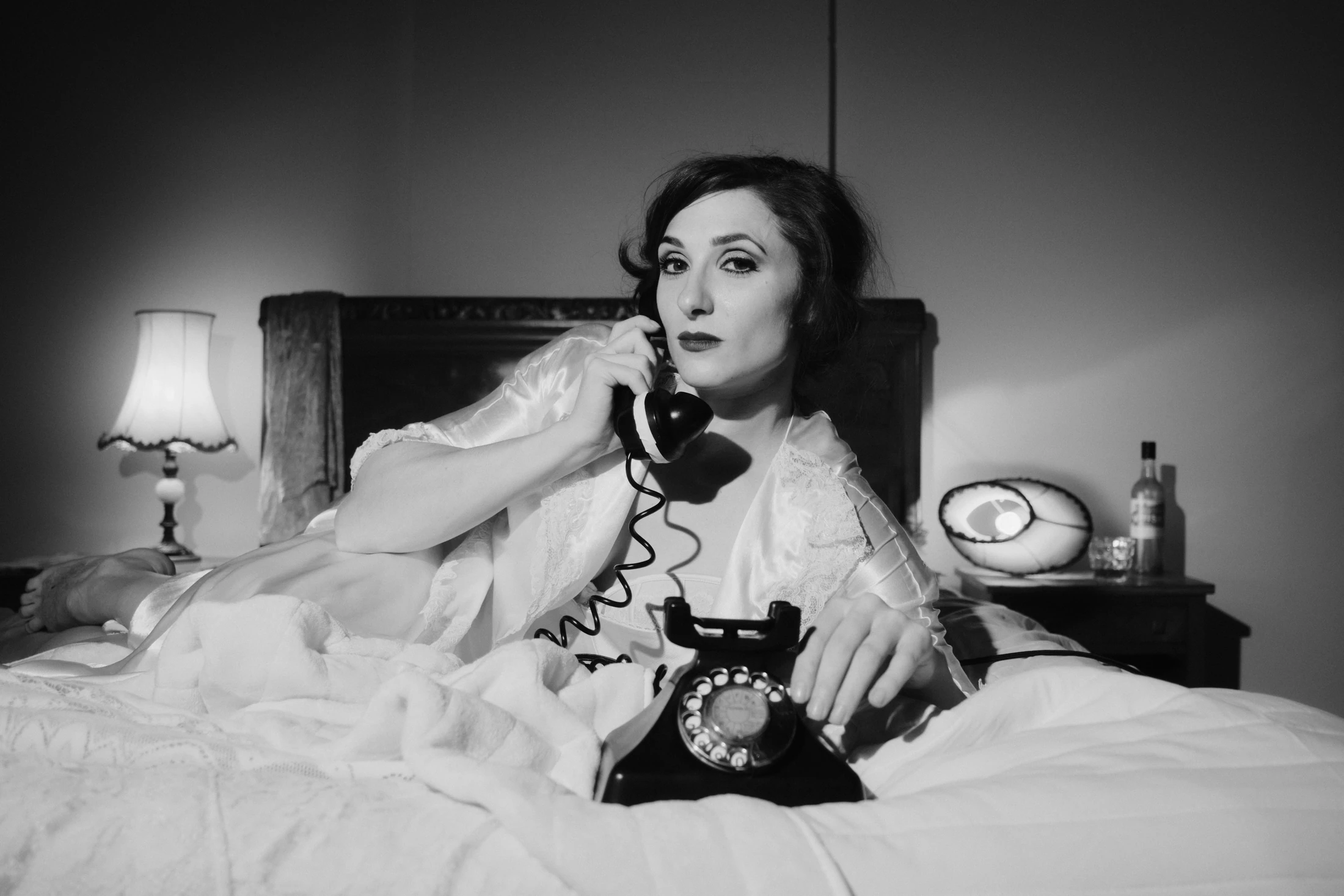 Black and white: a singer lies across a bed holding a telephone receiver