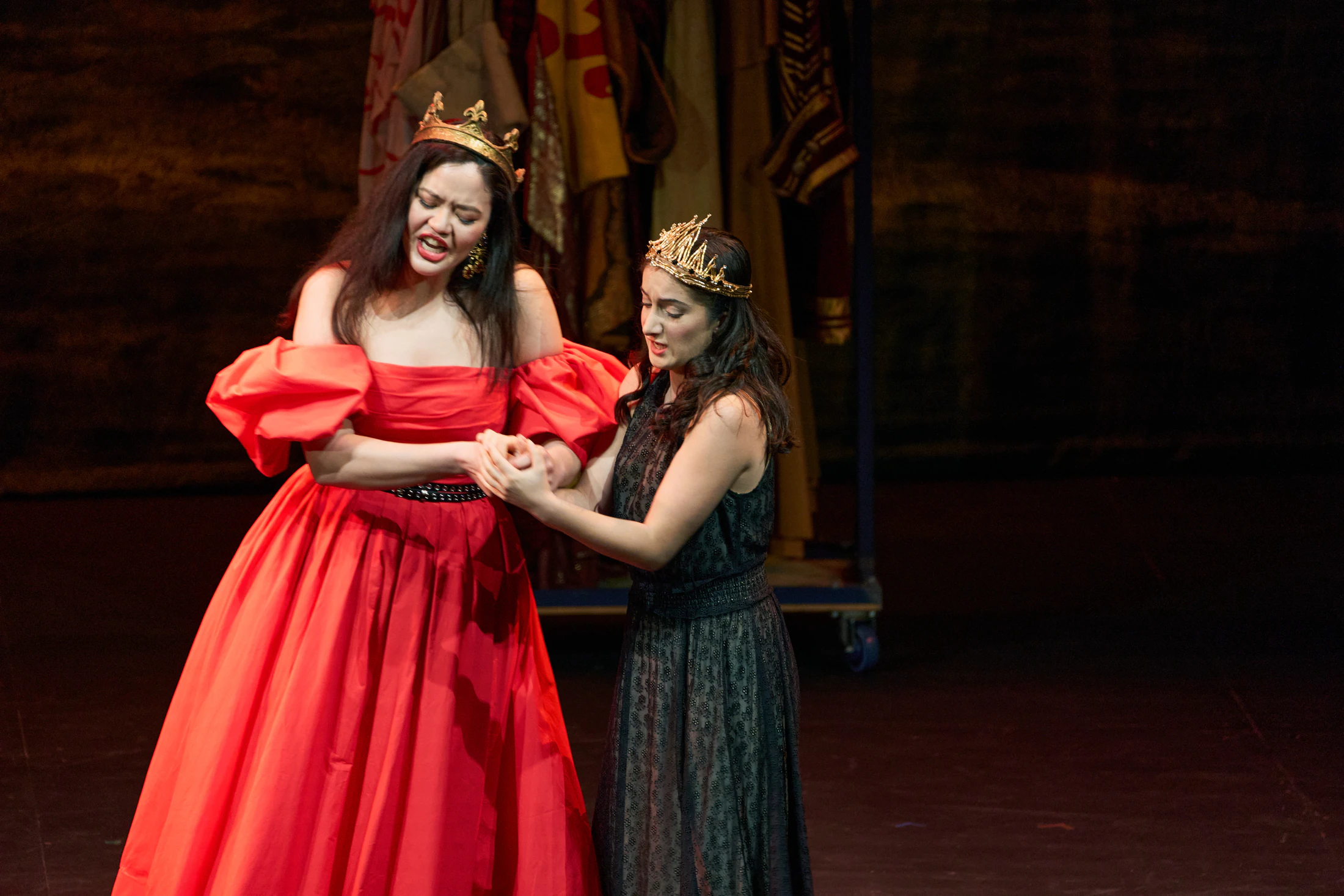 A singer in a red ball gown and a crowned singer in performance