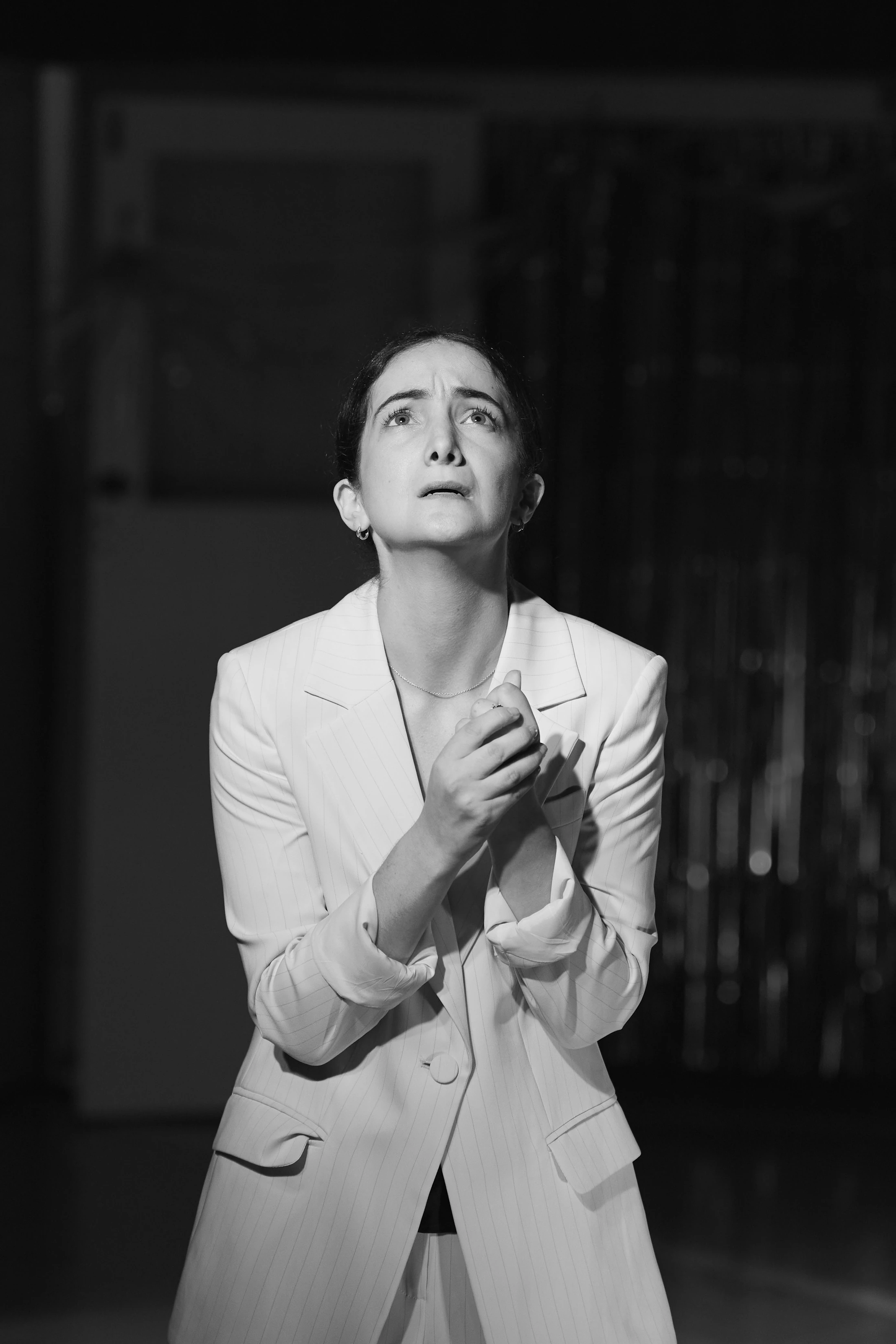 Black and white: a singer in a white suit, head bowed, hands clasped