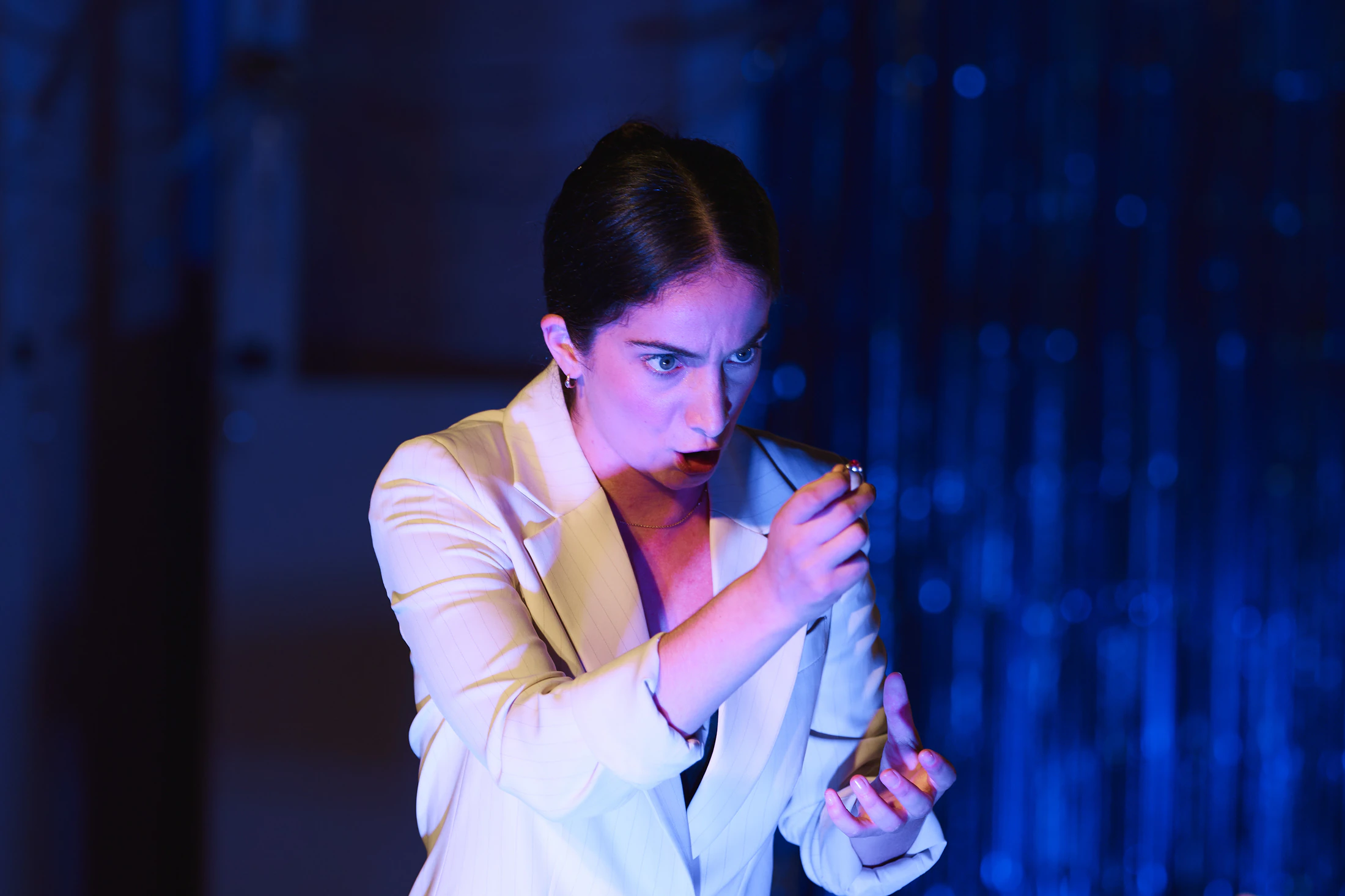 A singer in a white suit under blue light