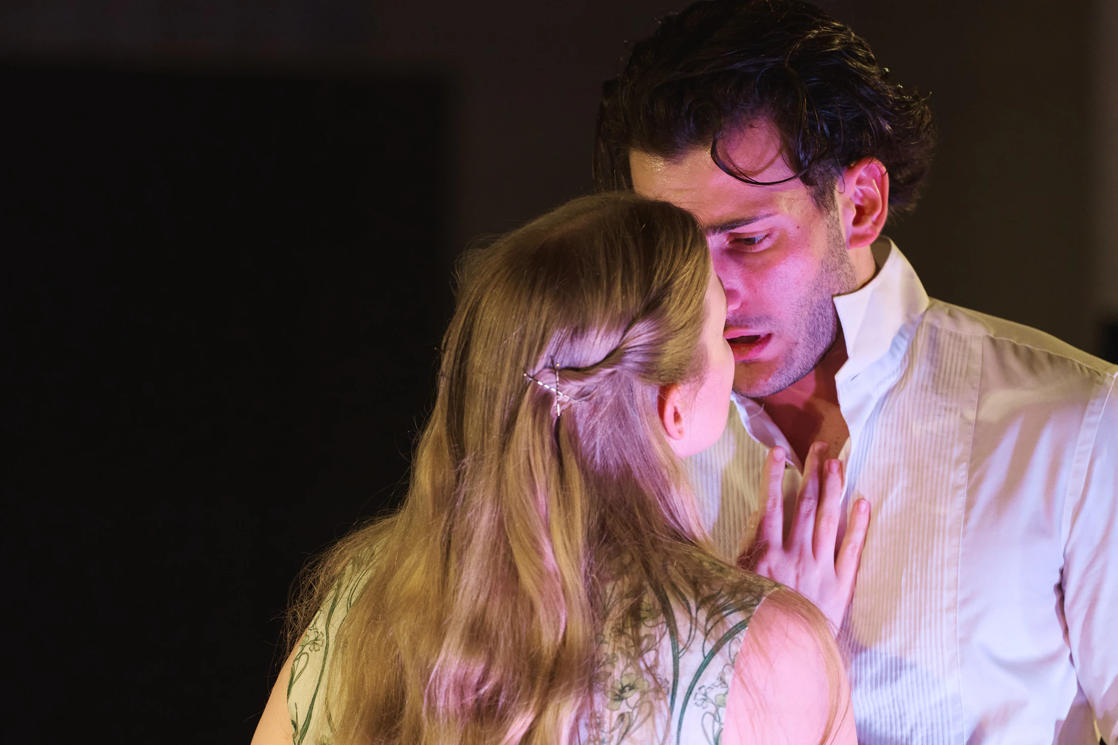 Two singers in a close embrace under a warm spotlight