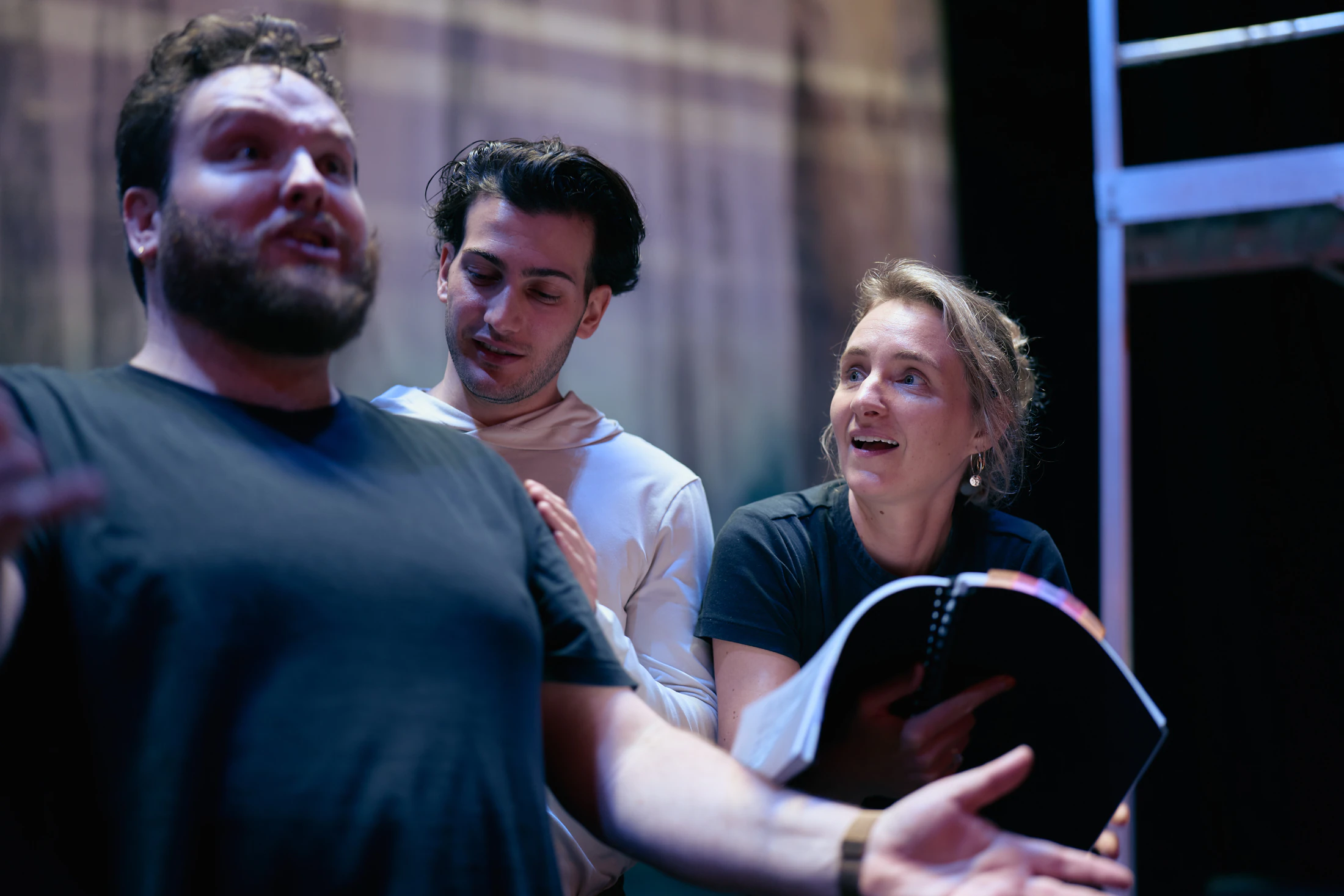 Three singers rehearse a scene, one holding a score
