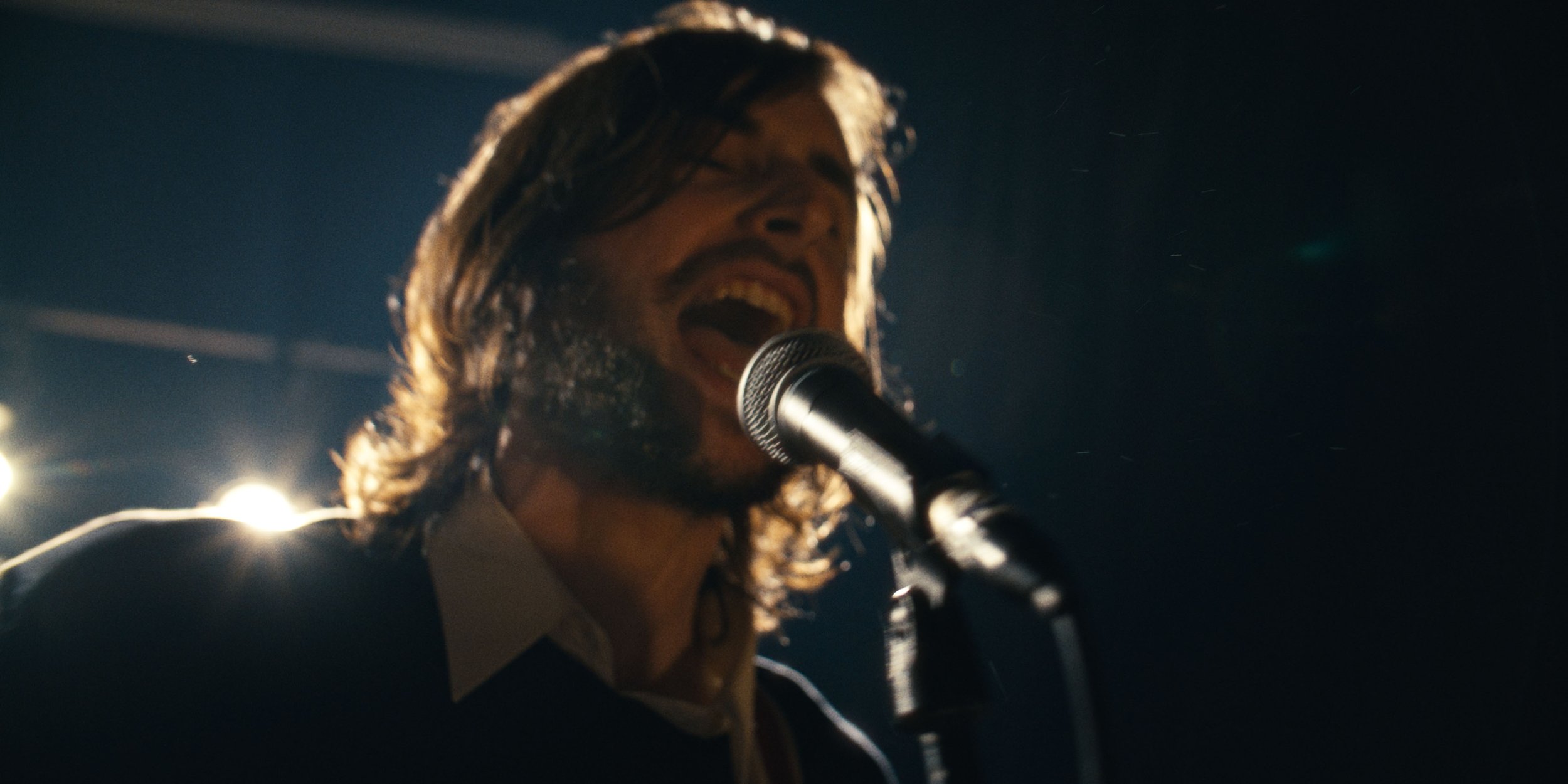 A long-haired singer belts into the microphone