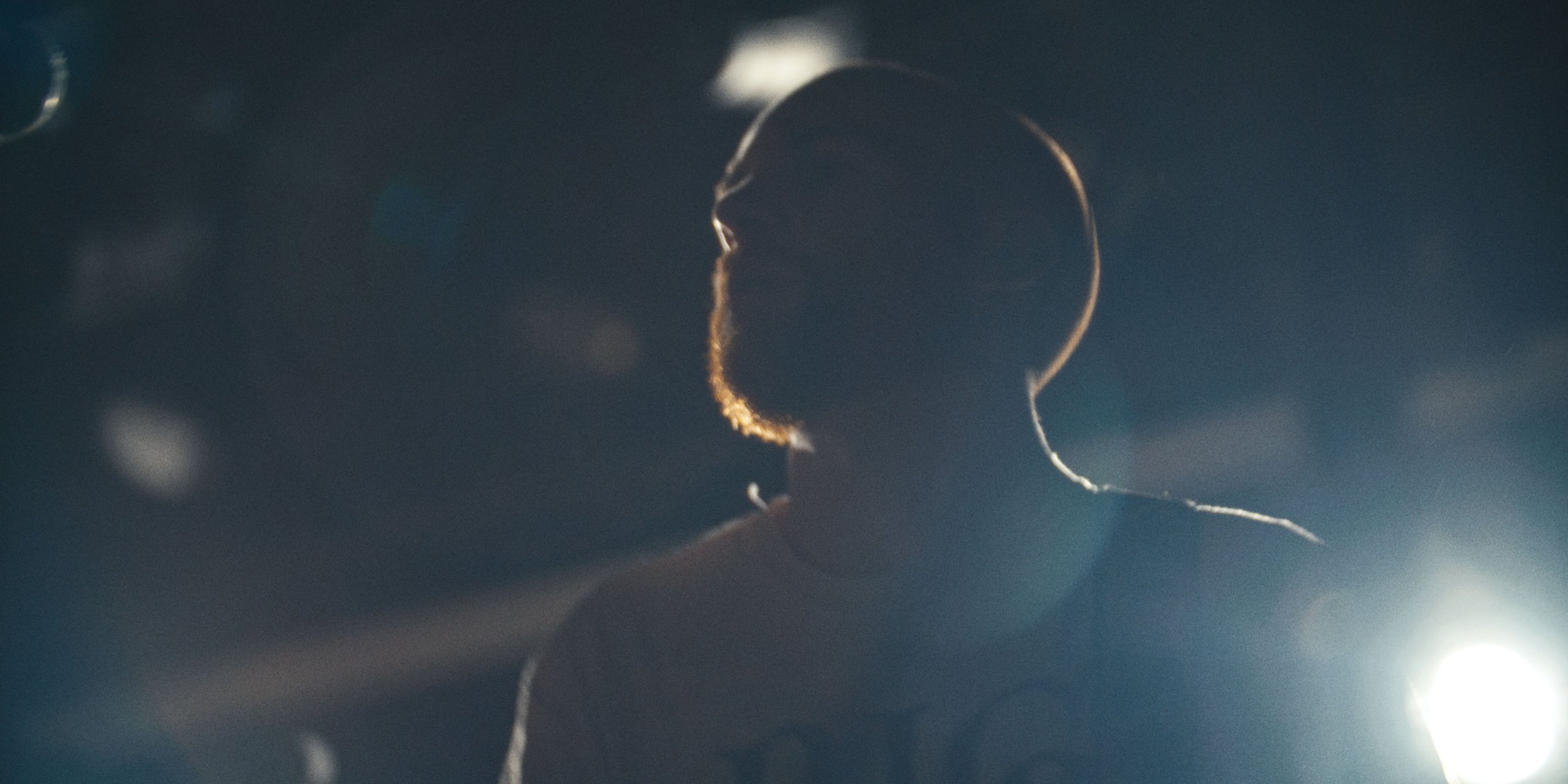 A band member in soft-focus silhouette under a blue light