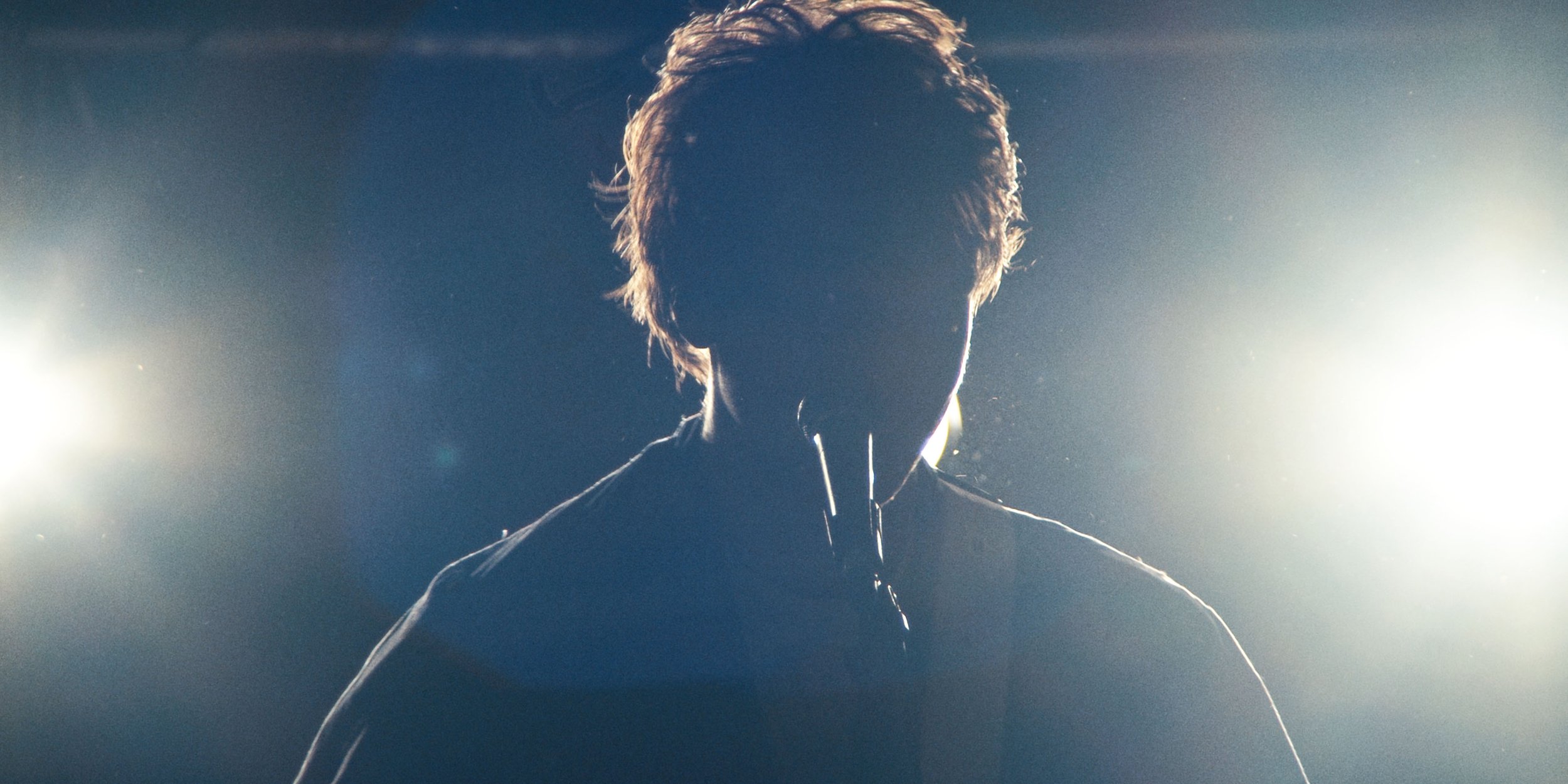 The singer in silhouette against two bright stage lights