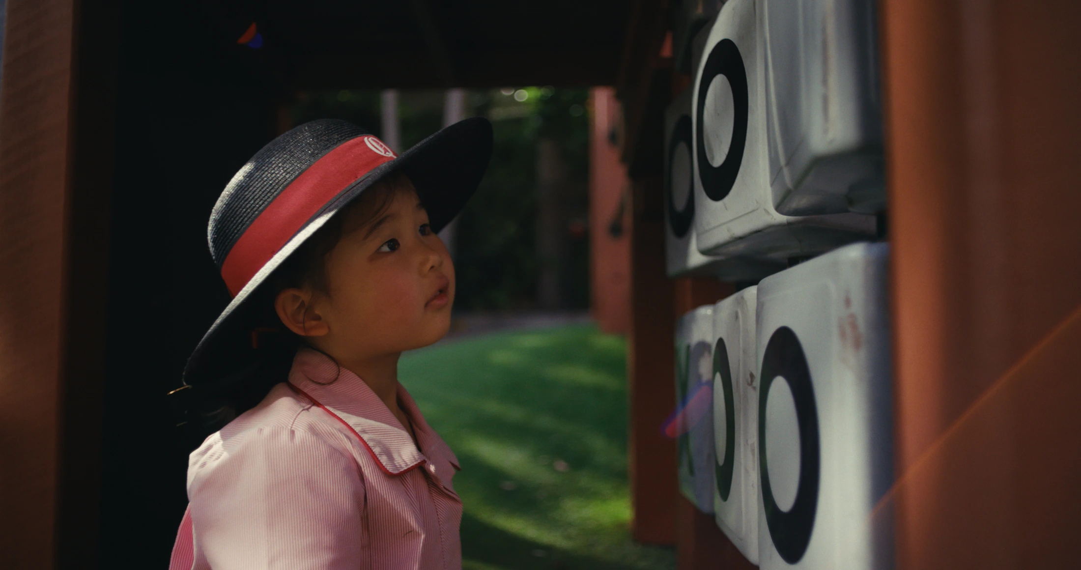 A young student in a straw boater looks up past a painted wall in the playground