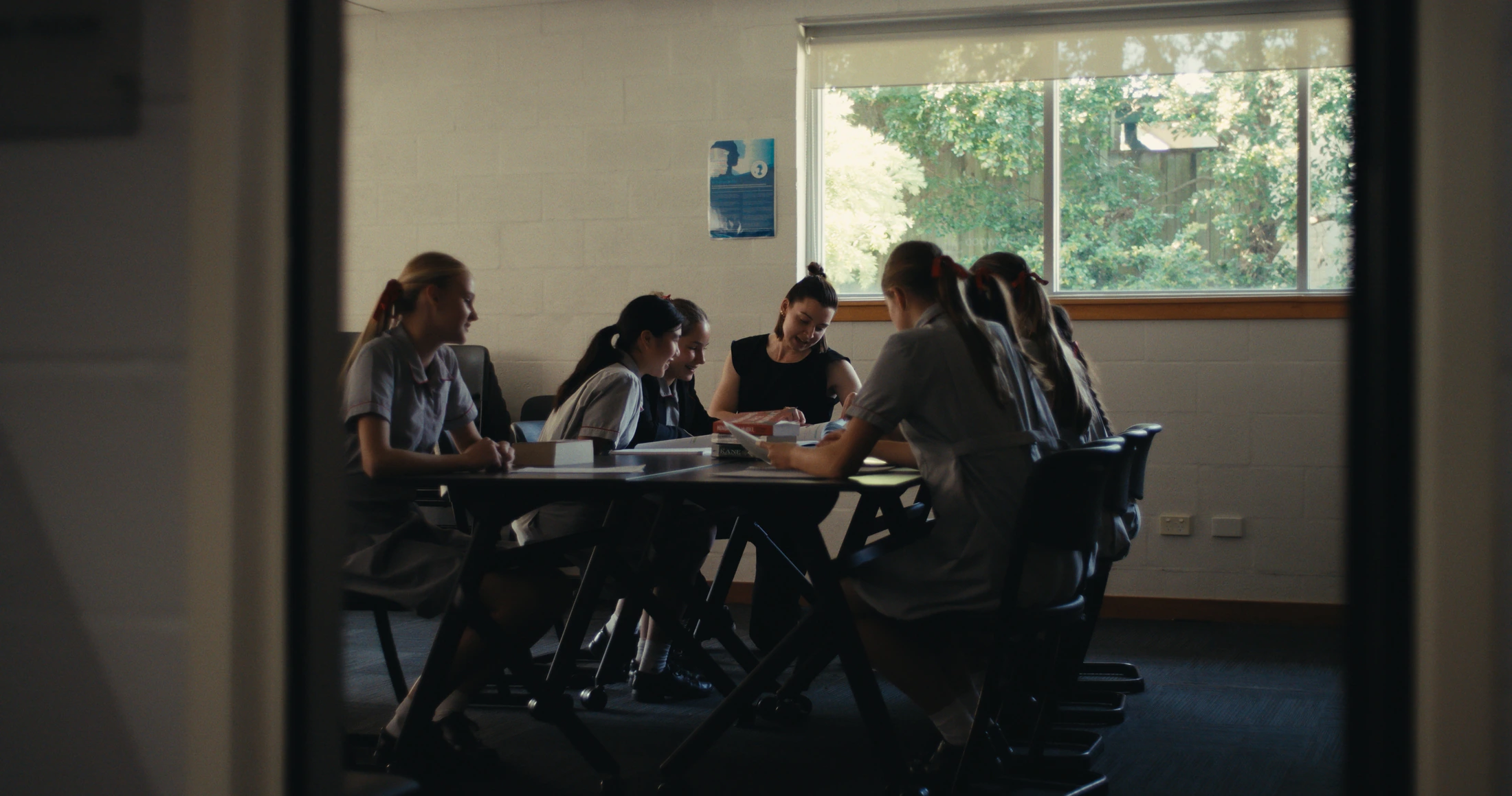 Students in grey summer uniform work around a table in a classroom