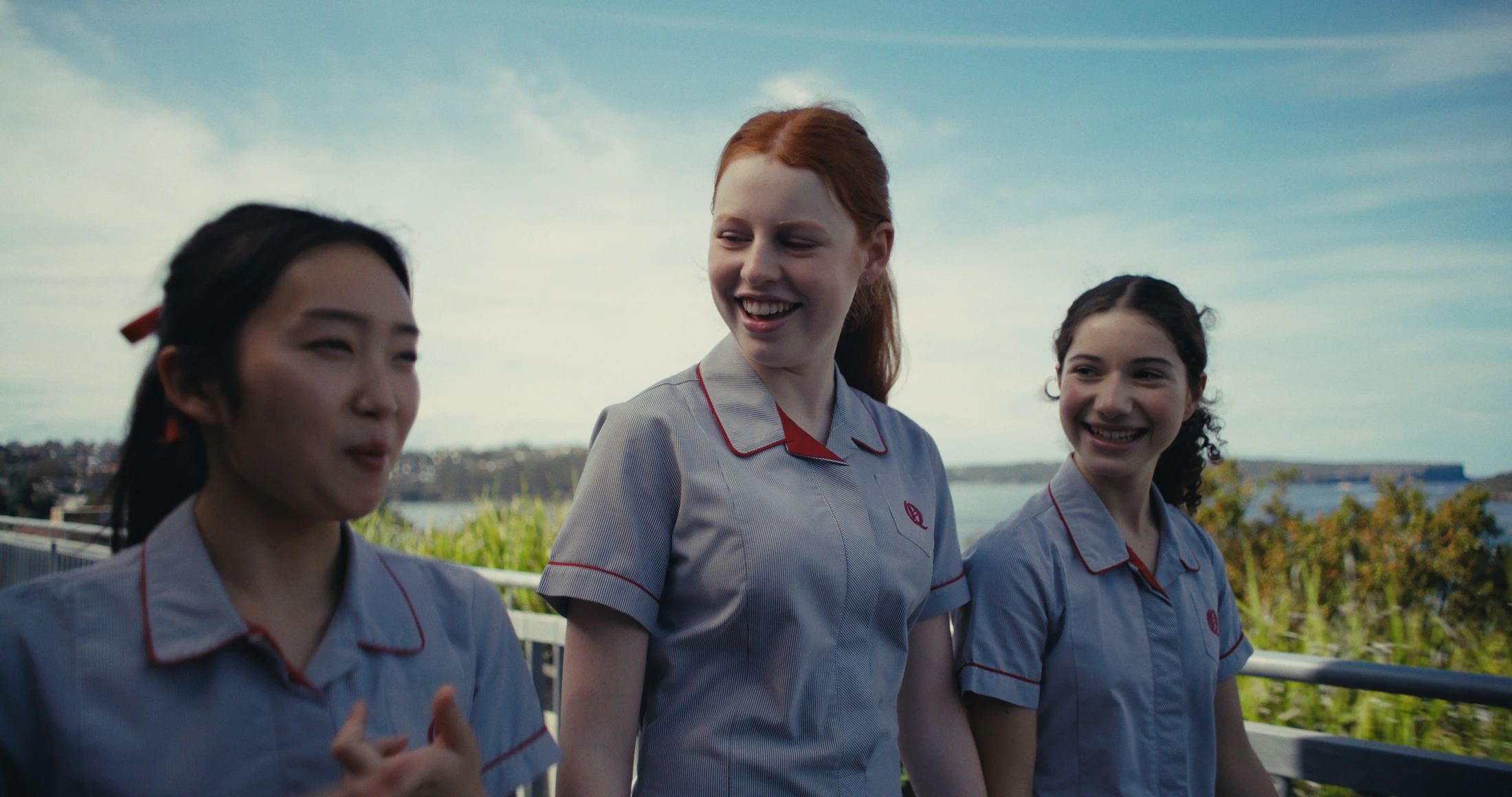 Three senior students talk and laugh by the harbour