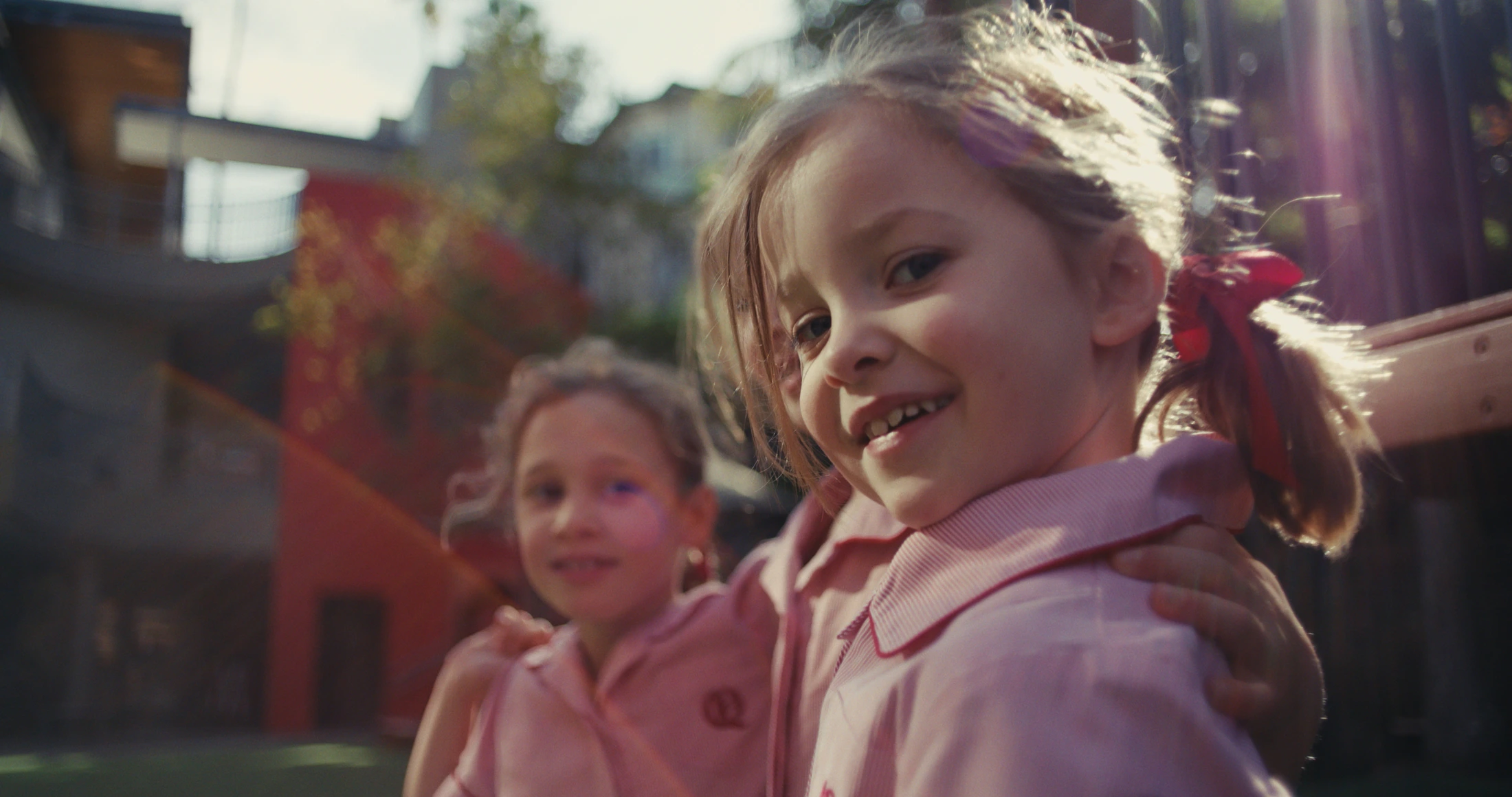 Two junior students lean in close and smile at the camera
