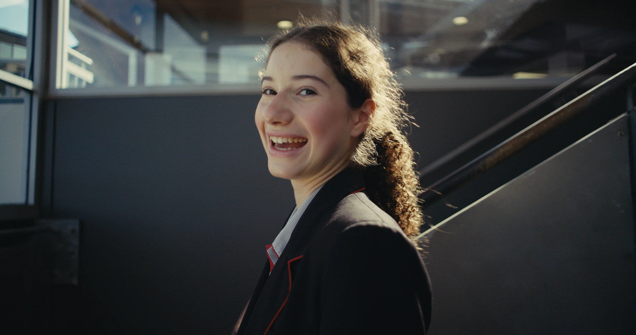 A senior student smiles back over her shoulder on a staircase