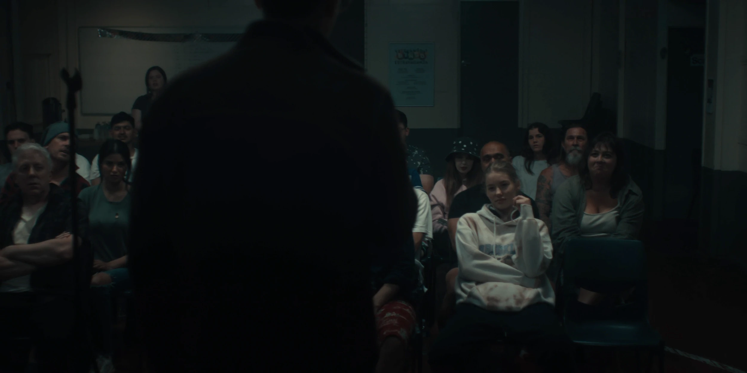The audience looks on past a dark figure standing in the foreground