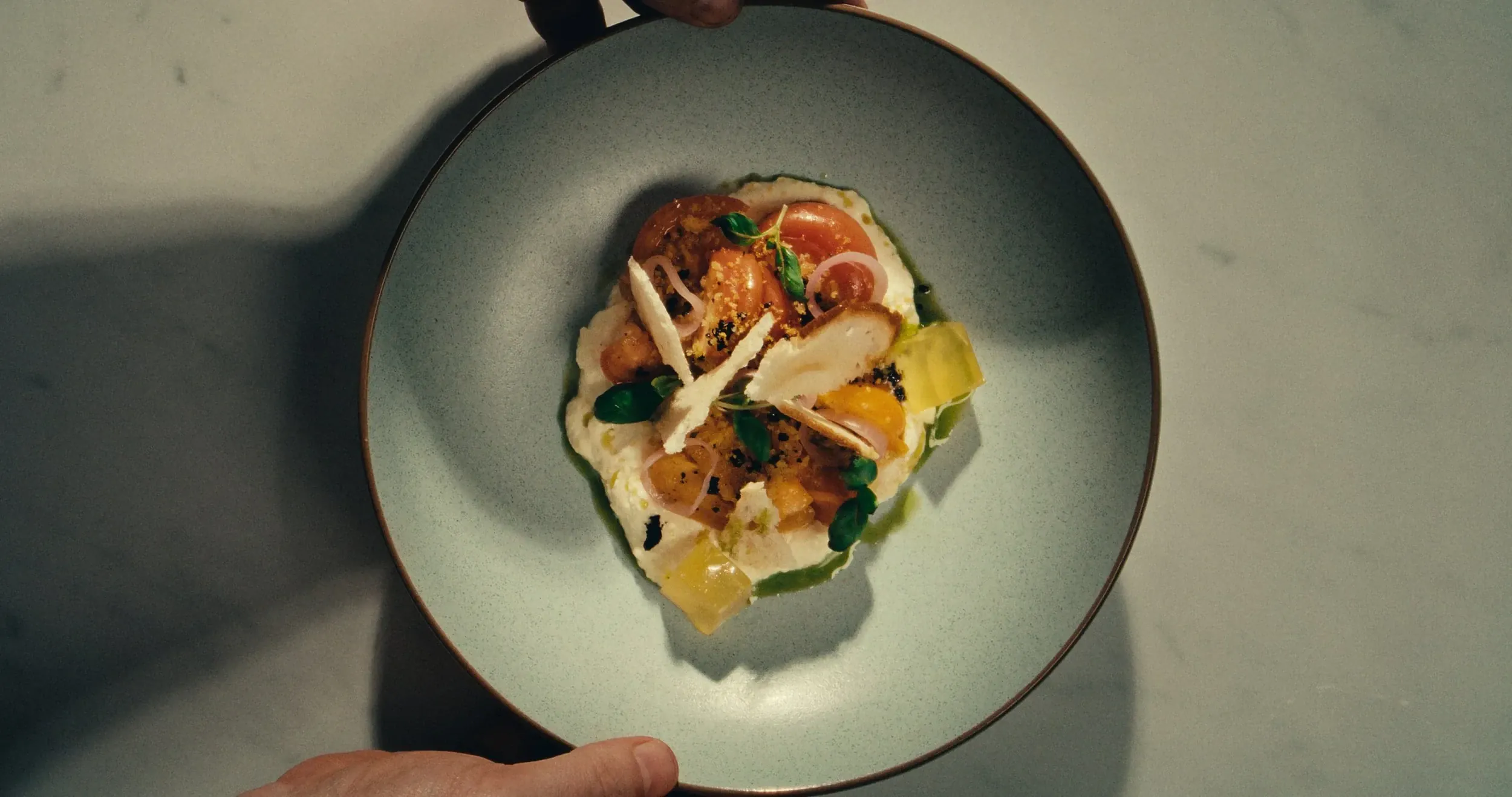 A plated dish held over a marble bench, seen from above