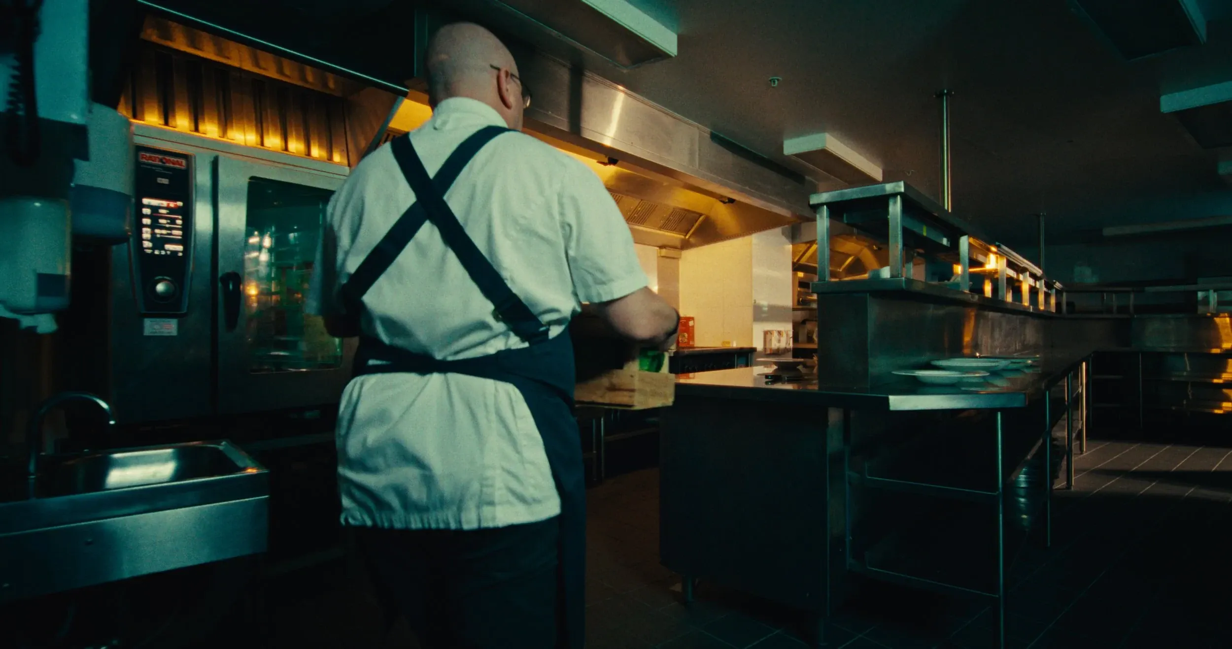 A chef works at the pass of a commercial kitchen